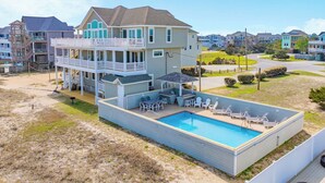 A two-story house with a pool, outdoor seating, and a deck. - Premier Oceanfront Home in Waves w/ Private Pool, Hot Tub, Game Room, Tiki Bar (Waves)