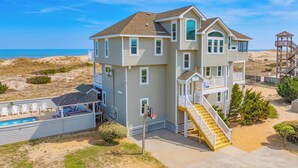 A multi-story beachfront house with a balcony, a pool, and a staircase leading to the upper levels. - Premier Oceanfront Home in Waves w/ Private Pool, Hot Tub, Game Room, Tiki Bar (Waves)