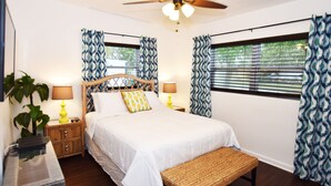 A bedroom with a bed, two bedside tables with lamps, a ceiling fan, and a window with curtains. - Corner-Lot 3 Bedroom House, renovated, short walk to the beach! (Cape Canaveral)