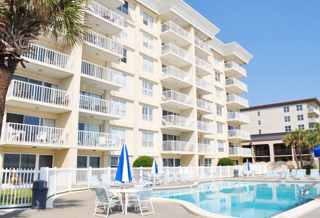 A multi-story hotel with balconies, a swimming pool, and outdoor seating.