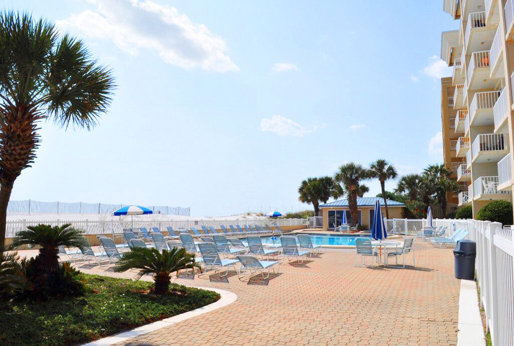 Un espace aménagé au bord de la piscine, avec des chaises longues, des parasols et une piscine.