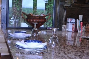 A kitchen counter with a decorative bowl, two plates, and a wine glass. - Secluded, luxurious cabin perched above Eagle Fork Creek with sunrise views. (Smithville)