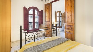 Una camera da letto con un letto, un armadio in legno, uno specchio e una porta finestra con accesso al balcone.