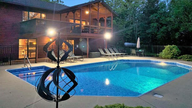 Ein zweistöckiges Haus mit Swimmingpool, Sitzgelegenheiten im Freien und einer dekorativen Metallskulptur.
