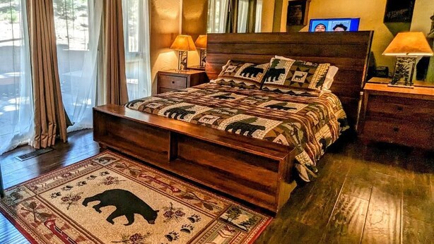 Ein großes Bett mit einem gemusterten Überwurf, zwei Nachttischlampen und einem Holz-Kopfteil.
