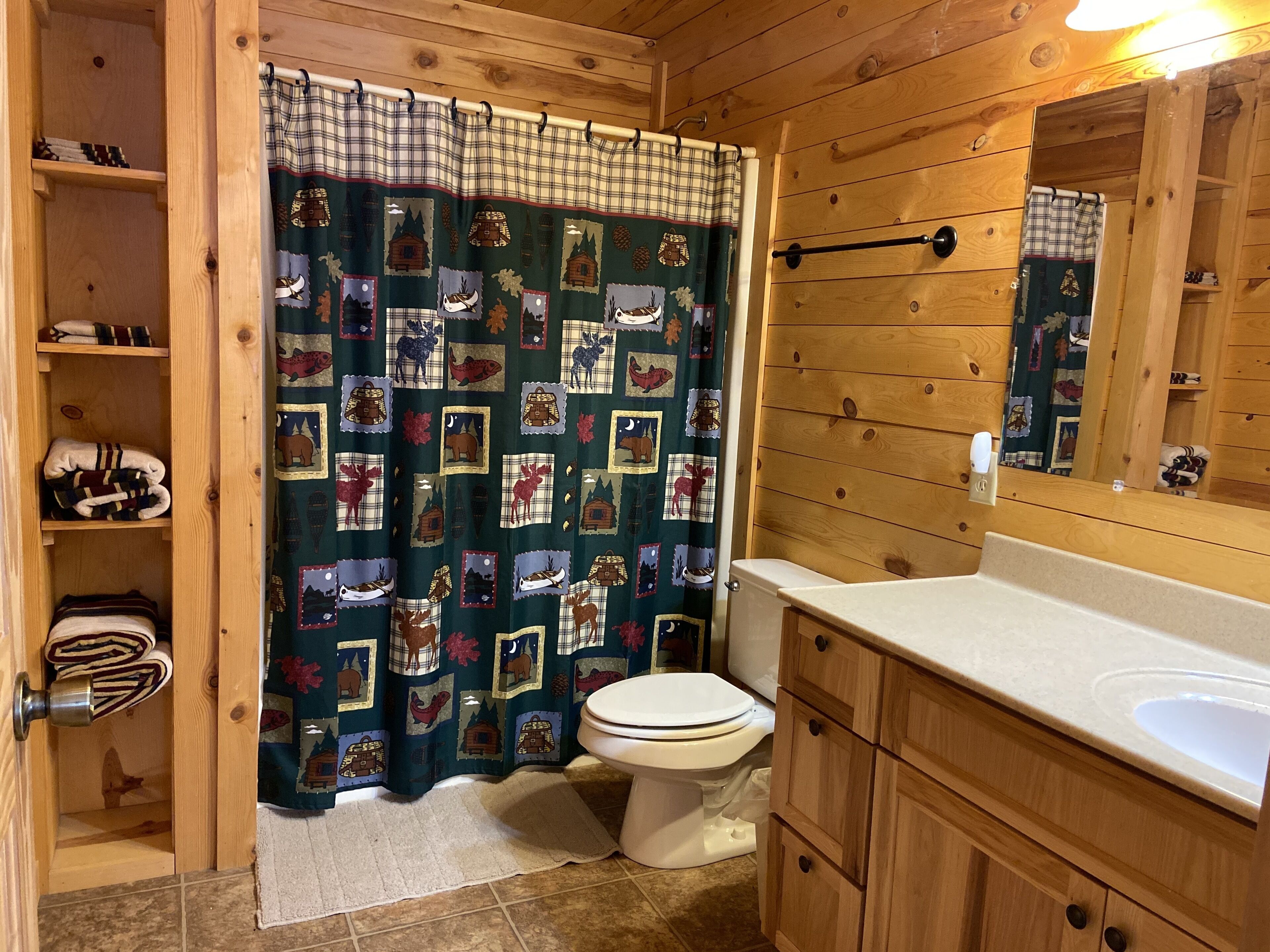 A wooden cabin bathroom with a toilet, sink, and shelves.