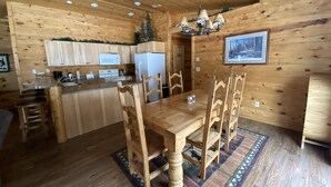 L’intérieur d’une cabane en bois comprend une cuisine, un coin repas et un plafond doté d’un éclairage encastré.