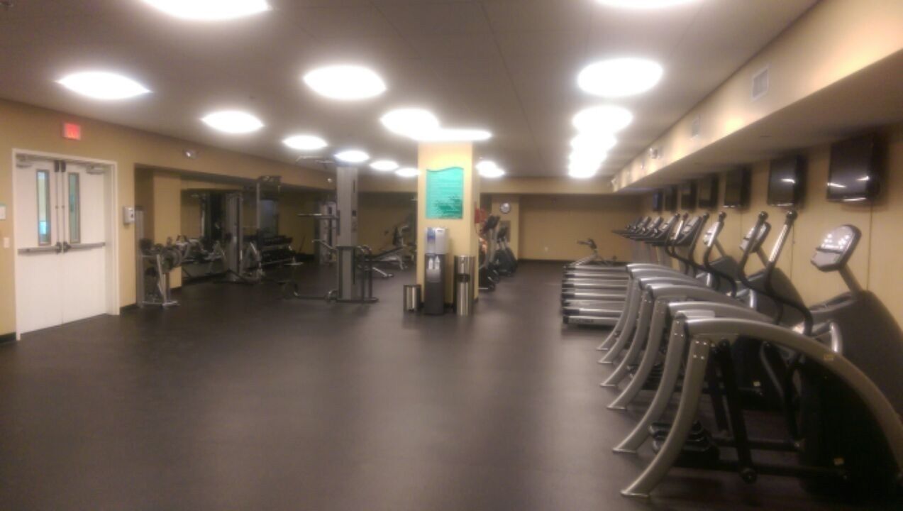 Ein Fitnessraum mit Trainingsgeräten, einem Trinkbrunnen und einem Spiegel.