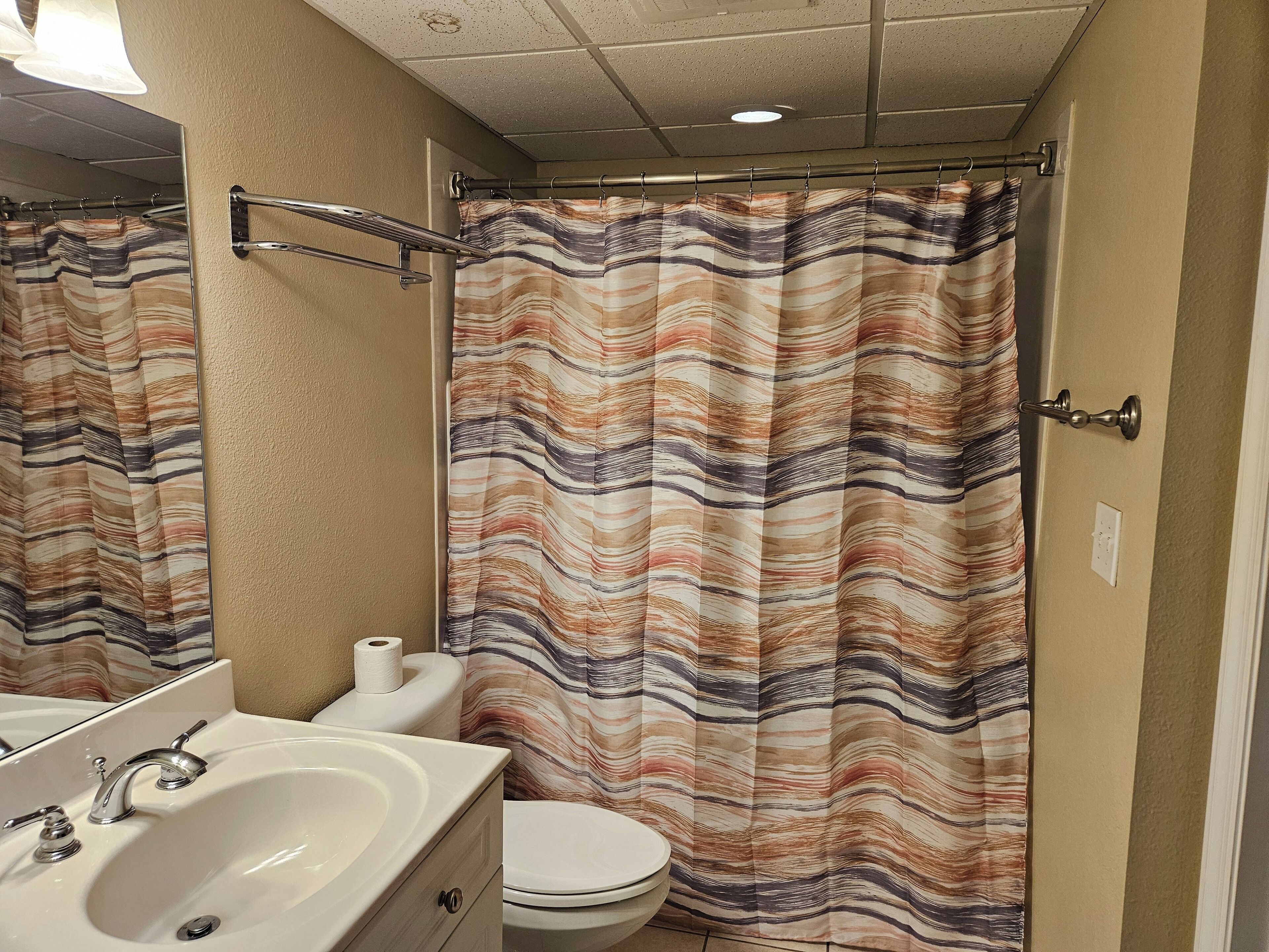 Un baño con cortina de ducha a rayas, un lavabo y un inodoro.