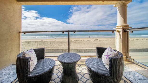 Ein Balkon mit Korbmöbeln und Blick auf den Strand.