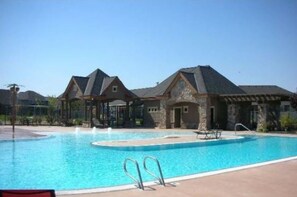 A swimming pool with two houses in the background.