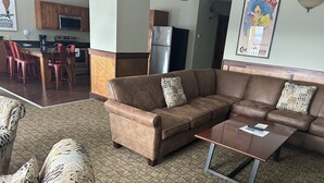 Ein Wohnzimmer mit braunem Sofa, gemusterten Kissen, einem Holztisch und einem Teppich mit Muster.