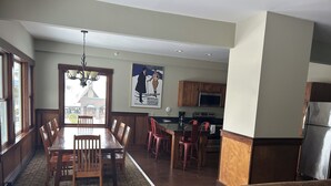 Ein Essbereich mit Holztisch und -stühlen, eine Küche mit modernen Geräten und ein Wohnzimmer mit einer Couch.