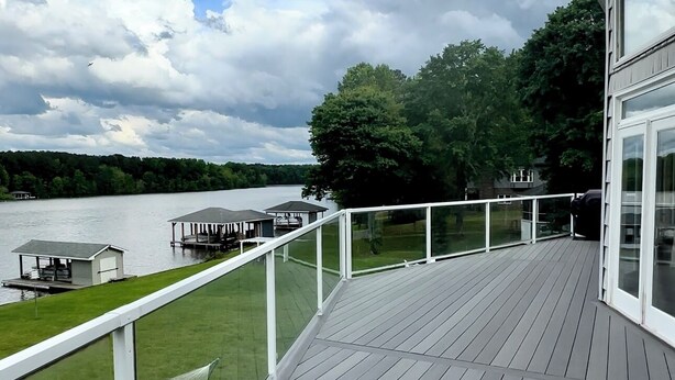 A wooden deck with a white railing overlooking a lake, a gazebo, and a grassy area. - Lake Escape - Unobstructed Views at our Group-Friendly Retreat! (Bracey)