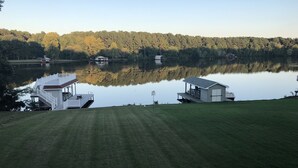 A lakeside property with a dock, a small cabin, and a large house with a deck. - Lake Escape - Unobstructed Views at our Group-Friendly Retreat! (Bracey)