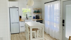 Une cuisine moderne avec des meubles blancs, un îlot central et un ventilateur de plafond.