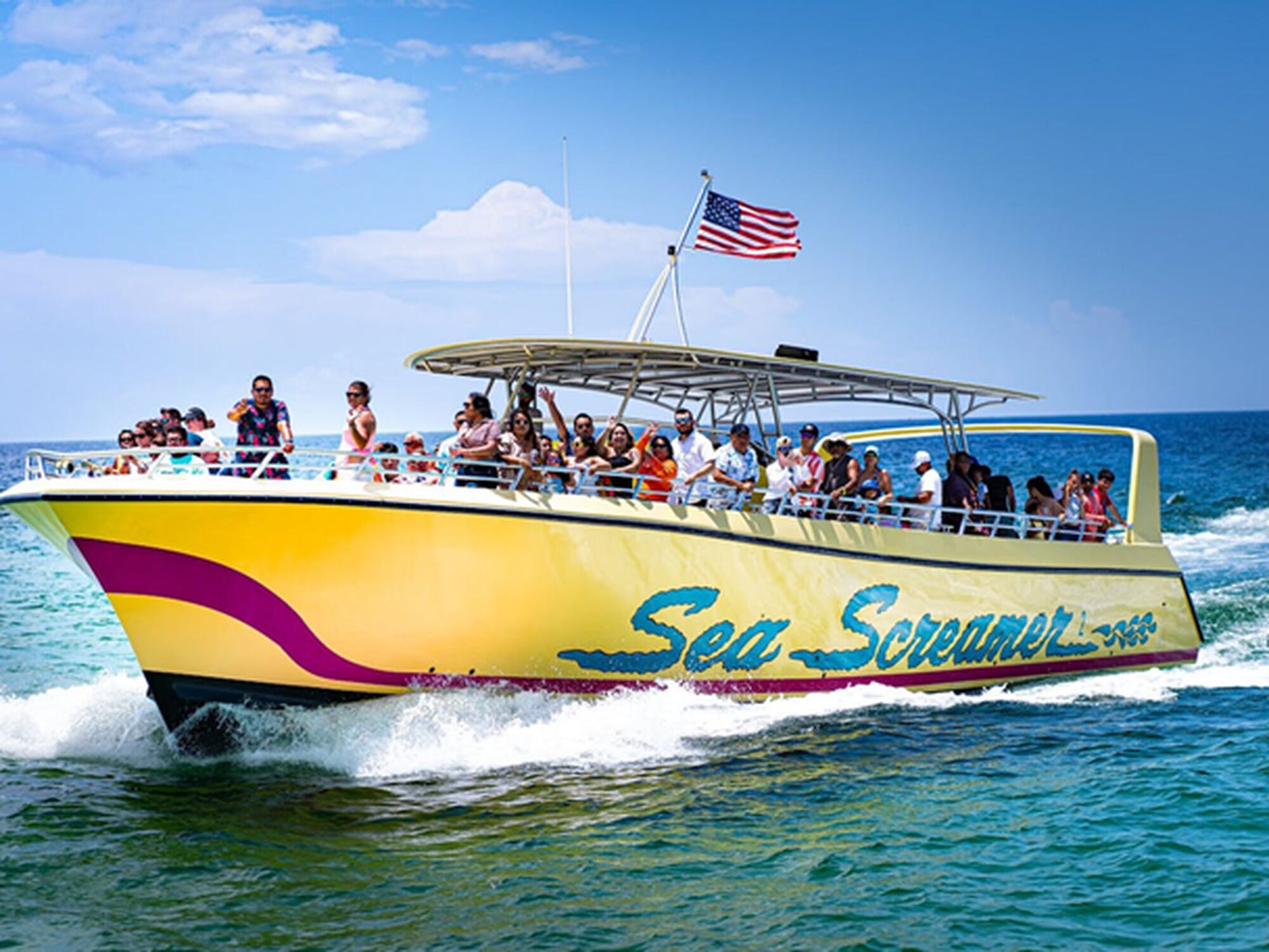 Un bote amarillo con la leyenda "Sea Screamer" en el costado, transportando pasajeros.
