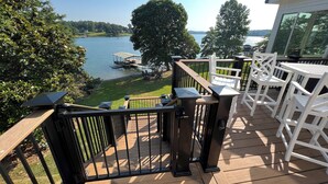 A deck with a view of a lake, a dock, and a grassy area. - Beautiful large family home with dock on Lake Keowee! (Seneca)