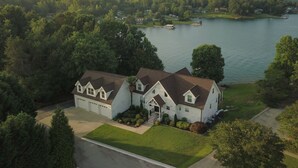 A large, two-story house with a garage, surrounded by a well-maintained lawn and trees. - Beautiful large family home with dock on Lake Keowee! (Seneca)