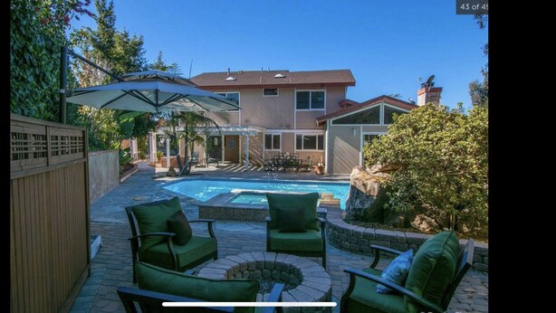 A backyard with a swimming pool, outdoor furniture, and a covered patio area.