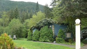 Una casa circondata da vegetazione lussureggiante, con un giardino curato e una montagna sullo sfondo.