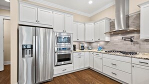 A modern kitchen with white cabinets, stainless steel appliances, and a tiled backsplash.