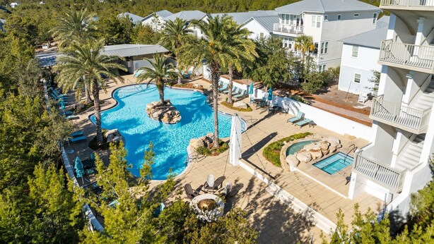 A resort with a large pool, multiple lounge areas, and a view of the surrounding forest.