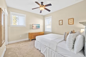 A bedroom with a bed, a ceiling fan, a dresser, and two windows. - Golf Cart & 4 Bikes! Next to Huge Resort Pool! Sandy Curls Cottage Highland Parks (Santa Rosa Beach)