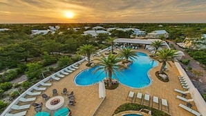 A resort with a swimming pool, lounge chairs, and palm trees. - Golf Cart & 4 Bikes! Next to Huge Resort Pool! Sandy Curls Cottage Highland Parks (Santa Rosa Beach)