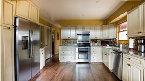 A kitchen with white cabinets, stainless steel appliances, and a wooden floor. - Spacious Prescott Forest Cabin, Game Room, 15 minutes to Downtown Prescott (Prescott)