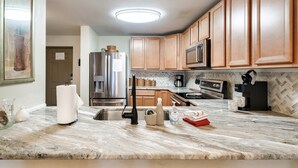Una cocina moderna con armarios de madera, electrodomésticos de acero inoxidable y encimera de mármol.