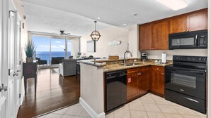 A modern kitchen with wooden cabinets, a granite countertop, and a view to the outside.