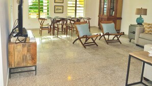 A spacious living area with a dining table, chairs, a television, and a cabinet.
