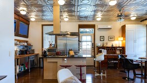 A modern kitchen with a central island, stainless steel appliances, and a bar area with stools. - Porch House W/Swim Spa/Pool &3 Big Screens To Enjoy  (New Orleans)
