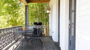 A wooden deck with a grill and table, surrounded by a metal railing and potted plants. - Porch House W/Swim Spa/Pool &3 Big Screens To Enjoy  (New Orleans)