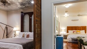 A hotel room with a wooden door, a bed with white bedding, a blue dresser, and a green leather chair. - Porch House W/Swim Spa/Pool &3 Big Screens To Enjoy  (New Orleans)