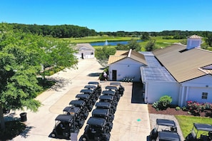 Un parcours de golf doté d’un bar servant des collations, d’une rangée de voiturettes de golf et d’un bâtiment dont le toit est en pente.