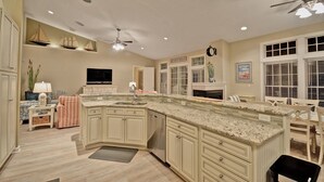 A spacious kitchen with a large island, a dining area with a table and chairs, and a ceiling fan. - Stunning 6 bedroom 3.5 bath House in Bear Trap Dunes Community! Wifi Available, Pool, Fitness Center, Beach Shuttle, Tennis, Golf! (Ocean View)