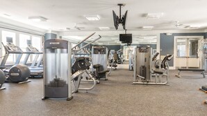 Een fitnessruimte met loopbanden, krachtapparaten en losse gewichten.