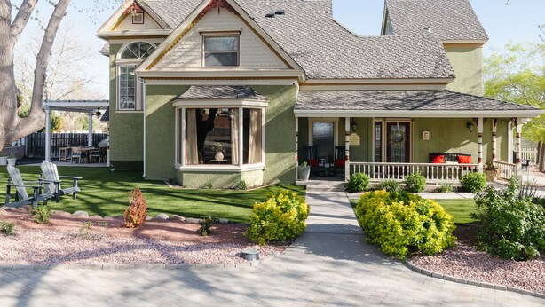 A two-story house with a porch, a small garden, and a patio area.