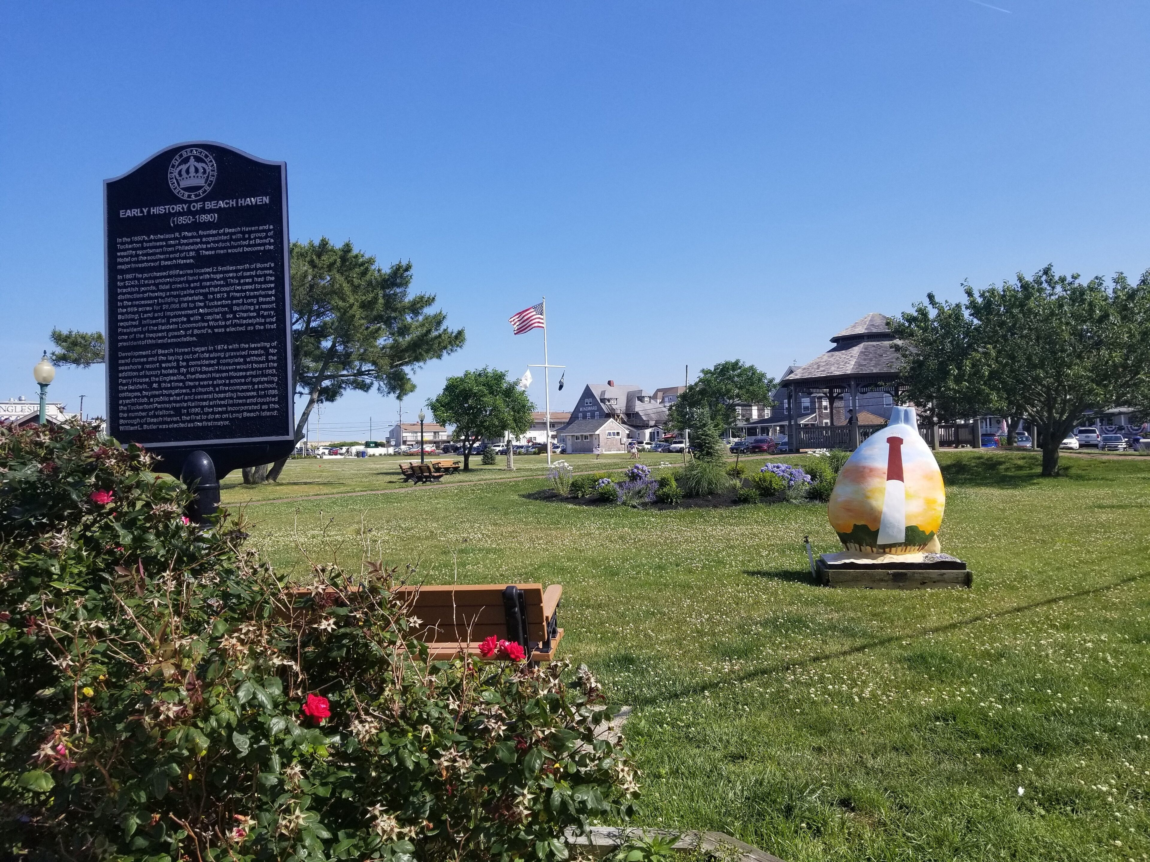 A park with a historical marker, a flag, and a unique sculpture.
