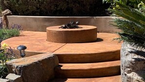 Un conjunto de escalones de piedra en terrazas que conducen a una plataforma circular de piedra con una escultura de un ave.