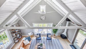 A spacious loft with a high ceiling, a central clock, and a cozy seating area with a coffee table. - Privacy and Views on Nantucket Island (Nantucket)
