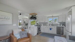 A modern kitchen with white cabinets, stainless steel appliances, and a hanging pot rack. - Privacy and Views on Nantucket Island (Nantucket)