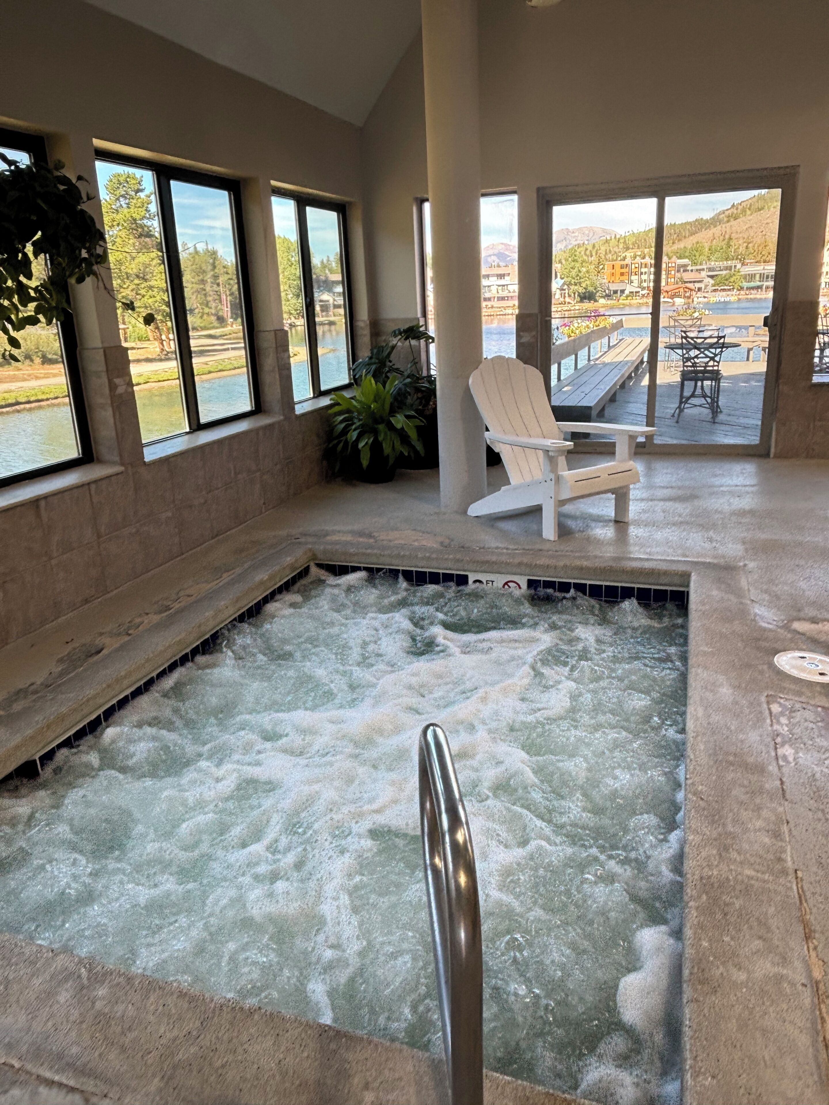 A spa area with a hot tub, a white chair, and a view of a lake and buildings.