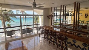 A bar area with a view of the ocean, a ceiling fan, and a tiled floor. - Oceanfront double size beach condo in La Sirena condominium (Akumal)