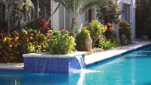 A swimming pool with a blue tiled edge and a waterfall feature. - Oceanfront double size beach condo in La Sirena condominium (Akumal)