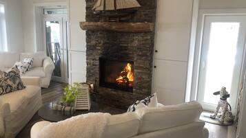 Ein Wohnzimmer mit Kamin aus Stein, weißen Sofas und einer Hundestatue.