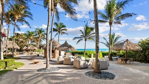 A resort with thatched-roof structures, outdoor seating, and palm trees.