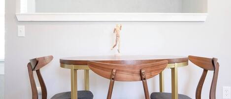 Un comedor con una mesa redonda y cuatro sillas de madera con asientos acolchados.
